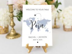 a welcome sign with a world map on it and gold candlesticks in the background