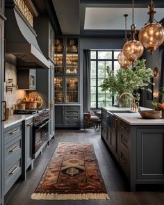 a large kitchen with lots of counter space and hanging lights over the stove top oven