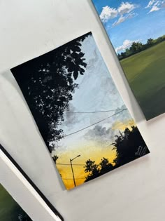 three paintings hanging on the wall in front of a white table with a pen and pencil