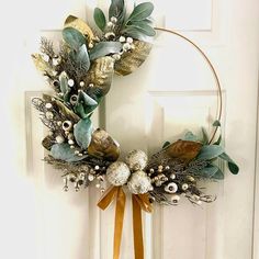 a wreath is hanging on the front door with gold and silver decorations around it, along with an orange ribbon