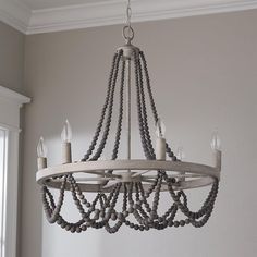 a wooden chandelier with beads hanging from it's centerpiece in a room