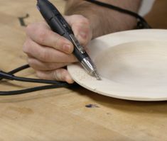 a person holding a pen and writing on a paper plate with wires attached to it