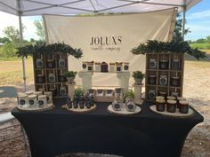 a table with bottles and candles on it under a white awning at an outdoor event