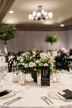 the table is set with white flowers and place cards for guests to sit down at