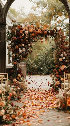 an outdoor wedding ceremony with flowers and petals on the ground in front of an arch