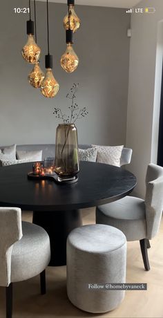 a dining room table with chairs and lights hanging from it's centerpieces