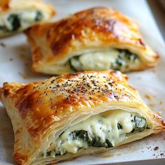 three pastries with spinach and cheese are on a baking sheet, ready to be eaten