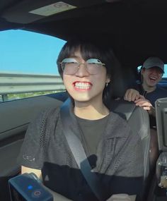 two people are sitting in the back seat of a car and one person is smiling