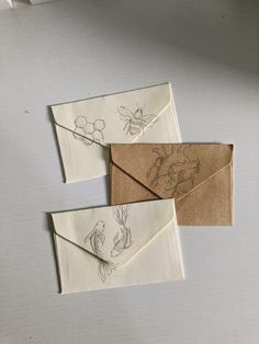 three envelopes with drawings on them sitting next to each other