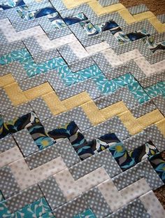 a close up of a quilt on the ground with blue and yellow squares around it