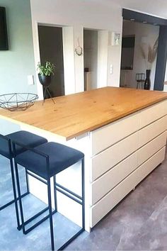 a kitchen island with two stools next to it and a television mounted on the wall