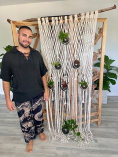 a man standing in front of a macrame wall hanging with plants on it