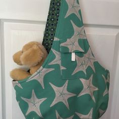 a stuffed animal in a green bag hanging on a door handle with starfish print