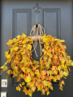 a wreath with yellow and orange leaves hangs on the front door's black door