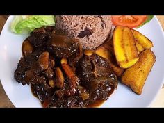 a white plate topped with meat and veggies covered in gravy next to rice