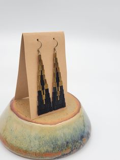 "Handwoven with nylon thread and Japanese glass beads in black and bronze, creating these elegant earrings that you can dress up or dress down.  Durable and lightweight, measuring 0.75\" wide and 3\" long, finished with 14K gold-filled ear wires. *Please keep away from water *Made to order - please allow 1 week before shipping" Handwoven Earrings, Woven Earrings, The Darkest Minds, Bugle Beads, Beaded Hoops, Triangle Shape, Brass Earrings, Elegant Earrings, Hand Woven