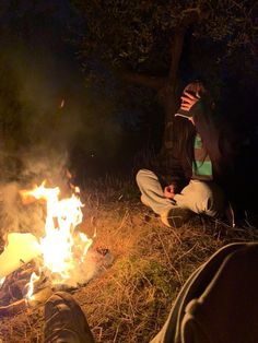 two people sitting around a campfire at night