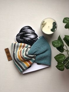 a knitted hat next to a cup of milk and a plant on a table