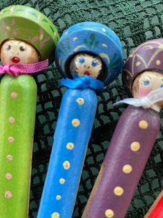 three colorful toothbrushes with little dolls in them sitting on a green tablecloth