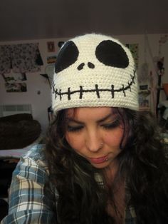 a woman wearing a crocheted hat with a skull on it's head