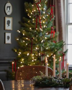 a christmas tree with lit candles in front of it and other decorations on the table