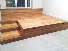 an empty room with wooden steps leading up to the window and storage drawers on the floor