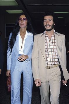 the man and woman are dressed up in matching outfits for an airport trip, one is holding his hand