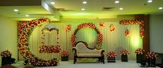 the stage is decorated with red and white flowers, green garlands, and an ornate mirror