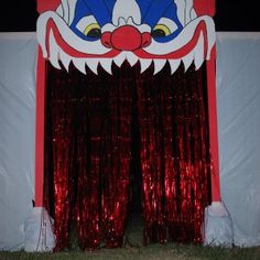 a red and white stage curtain with a dragon head on it's side in front of a wall