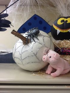 two small pigs sitting next to each other in front of pumpkins and spider web decorations