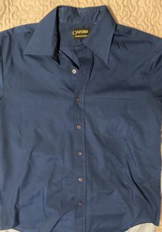 This Dark Blue Short Sleeve Dress Shirt from Oxford Shirt Makers is a must-have for any stylish wardrobe. Crafted with care from high-quality materials, this shirt offers exceptional comfort and durability that will last for years to come. Perfect for any casual or formal occasion, this shirt features a classic design that is both timeless and versatile. Its medium size makes it easy to wear and pair with your favorite clothing items. Add this shirt to your collection today and elevate your style with ease. Tag color is diff due to lighting Dark Blue Dress Shirt, Casual Navy Button-up Dress Shirt, Navy Cotton Pre-shrunk Shirt, Vintage Blue Button-up Shirt, Blue Relaxed Fit Button-up Dress Shirt, Short Sleeve Dress Shirt, Shirt Maker, Mens Oxfords, Oxford Shirt