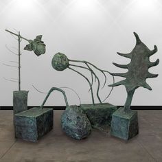 an abstract sculpture is displayed in front of a white wall and two square vases