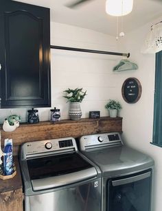 a washer and dryer in a laundry room with black cabinets, white walls and wood flooring