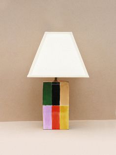 a multicolored lamp sitting on top of a table next to a white vase