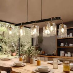 the lights are hanging over the table in the kitchen, with plates and cups on it