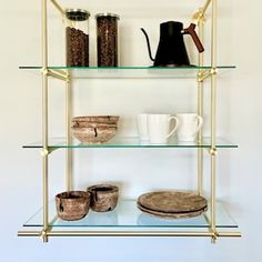 a shelf that has some cups and bowls on top of it with gold trimmings