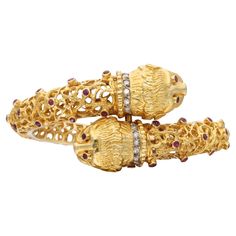 A two-headed chimera bangle bracelet made out of 18 karat yellow gold. It is sprinkled with rubies throughout, weighing approximately 2.70 carats. The necks of the two heads are lined with diamonds, weighing approximately 0.20 carat. Made in Greece. Total weight: 73.23 grams. Inner circumference: 6 inches. Yellow Gold Ruby Bangle Bracelets, Ruby Bangle Bracelet In Yellow Gold, Formal Yellow Gold Ruby Bangle, Two Heads, Bangle Bracelet, Bracelet Making, Gold Diamond, Cuff Bracelets, Bangle Bracelets