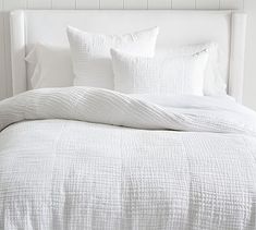 a bed with white sheets and pillows on it