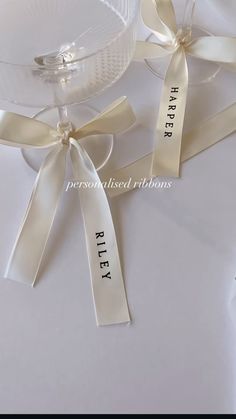 two wine glasses with ribbons tied around them on a white tableclothed table cloth