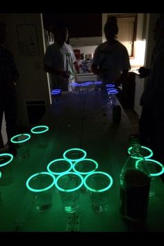 some people are standing around in the dark with glowing circles on the floor, and one person is looking at them