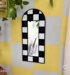 a black and white checkered mirror hanging on a wall next to a potted plant