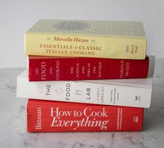 three books stacked on top of each other in front of a marble countertop with the title how to cook everything