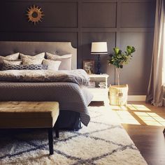 a bedroom with a large bed and wooden paneling on the wall, along with a bench in front of it