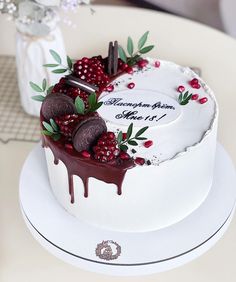 a white cake decorated with berries and chocolate