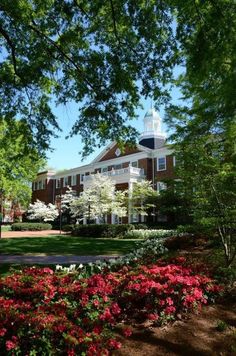 the building is surrounded by flowers and trees