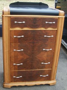 a wooden dresser with black leather top sitting in front of a trailer parked on the street