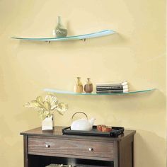 two floating shelves on the wall above a small table with an open drawer underneath it