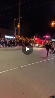 a group of people walking down a street next to a horse drawn carriage at night