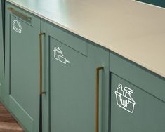 a kitchen with green cabinets and stickers on the doors, along with wooden flooring