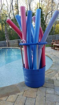 a blue bucket filled with lots of pink and blue toothbrushes next to a swimming pool